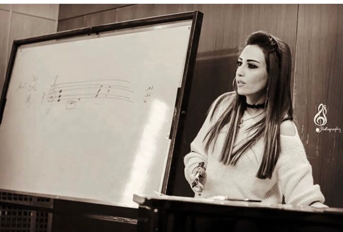 Salma geeft een muziektheorieles op het bord tijdens een workshop