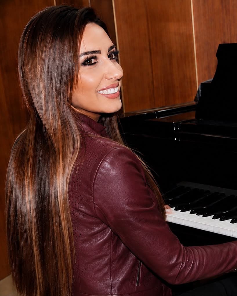 Salma glimlachend achter de vleugelpiano